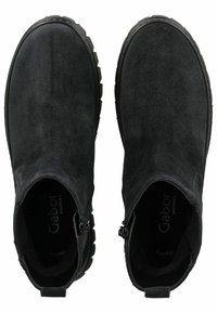 Bottines en suède noir avec un bout rond, des fermetures éclair sur les côtés et des semelles en caoutchouc texturé pour une adhérence, présentant une finition lisse et un design minimal.