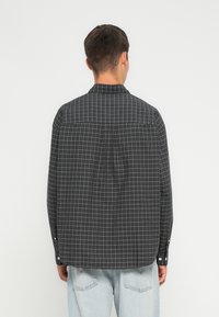 Svart og hvit rutete skjorte med knapp, med buet hem, lange ermer og klassisk krage, laget av et lett stoff.