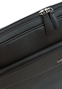 Schwarze Laptoptasche aus Leder mit strukturiertem Finish, ausgestattet mit doppelt Reißverschlüssen und einem dezenten Branding-Detail an der Seite.