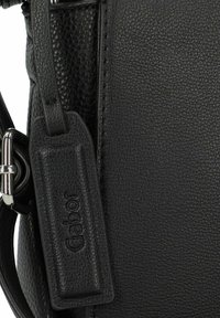 Borsa a mano in pelle nera con superficie texture, hardware argentato e un'etichetta con il marchio "Gabor" in rilievo.