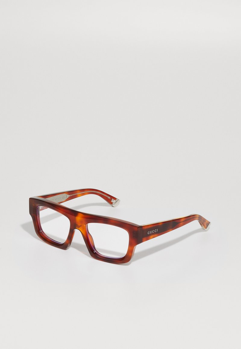 Gafas de tortuga marrón de Gucci con un marco rectangular grueso y sutiles acentos plateados en las patillas. Lentes transparentes sin prescripción.