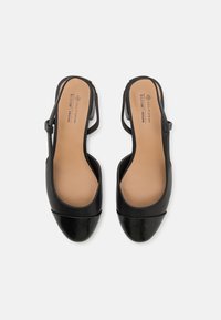 Escarpins vegans noirs à bride arrière avec un bout arrondi, un détail accent brillant noir à l'avant et une sangle étroite pour un ajustement sécurisé.