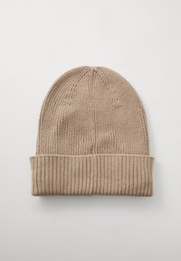 Strikket beige lue med ribbestrikket mansjett og glatt kropp, med avrundet topp og teksturerte sømdetaljer.