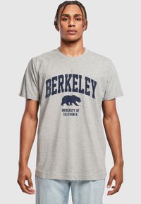 Šedé bavlněné tričko s nápisem "BERKELEY" v sytě modrém tučném písmu a grafikou medvěda, s nápisem "UNIVERSITY OF CALIFORNIA" pod ním. Standardní střih.