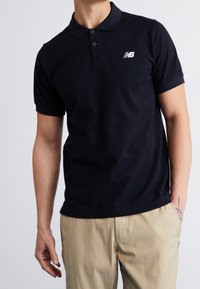 Polo navy de algodón, con una tapeta de tres botones, mangas cortas y un logo bordado blanco en el lado izquierdo del pecho.