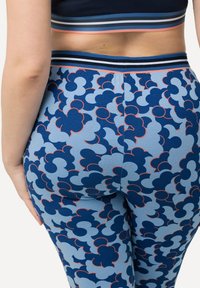 Blå leggings med ett blommönster i marinblått och ljusblått, med röda accenter. Mjuk tyg med en slät struktur och en åtsittande design.