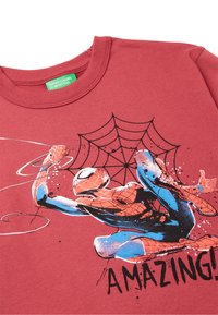Červené bavlněné tričko s grafikou Spidermana a designem pavučiny. Postava je znázorněna v modré a oranžové barvě, s nápisem "ÚŽASNÉ!" v tučném černém písmu.