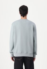 Felpa azzurra con collo a girocollo con costine, maniche lunghe e polsini a costine. Tessuto dalla superficie liscia, vestibilità comoda, design semplice.
