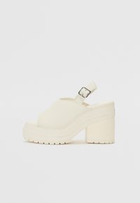 Sandales à talons plateforme en toile blanc cassé, avec bout ouvert et bride de cheville ajustable dotée d'une boucle métallique. Semelle texturée.
