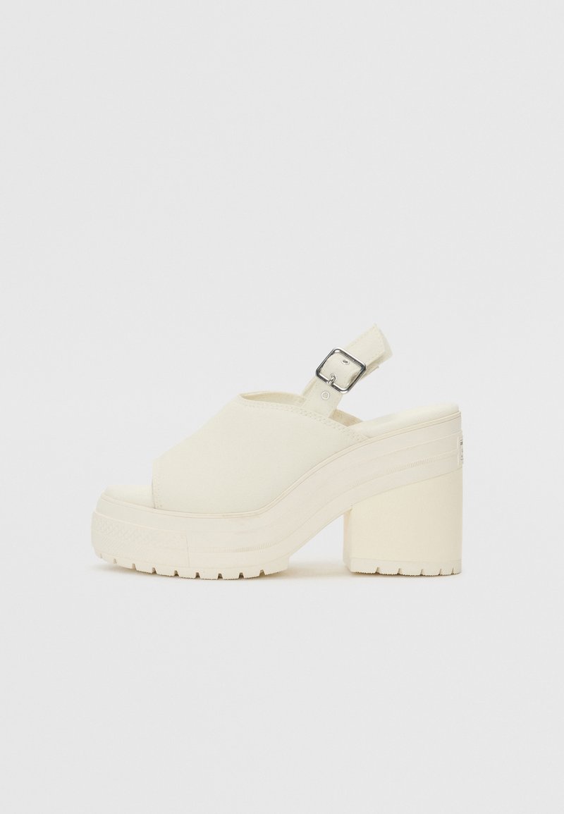 Sandales à talons plateforme en toile blanc cassé, avec bout ouvert et bride de cheville ajustable dotée d'une boucle métallique. Semelle texturée.
