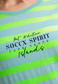 Light blue t-shirt with green horizontal stripes, featuring the text "Int. Edition SOCCX SPIRIT CAPE VERDE Islands" in black and green.