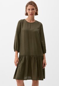 Gingham-Kleid in Olivgrün und Braun, mit rundem Ausschnitt, langen Ärmeln und einem rüschengesäumten Saum. Aus einem leichten Stoff gefertigt.