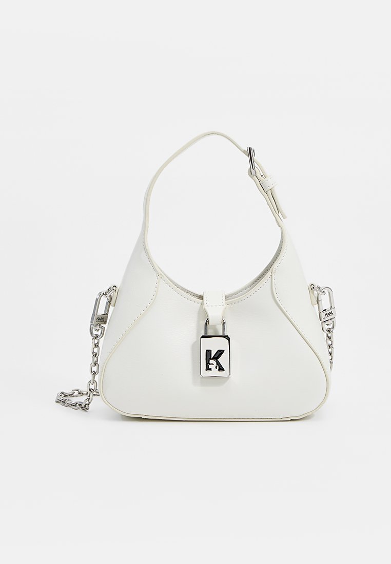 Sac à main en cuir synthétique blanc avec une forme courbée, un pendentif en forme de serrure avec un 'K', et une chaîne courte ainsi qu'une bandoulière réglable.