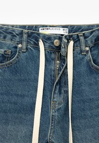 Jeans de mezclilla azul con cremallera y cierre de botón, que presentan un cordón blanco. Las etiquetas indican el tamaño W27 L32. La textura es suave con un ligero desvanecimiento.