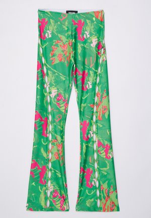 Leggings verdes acampanados con un patrón floral y abstracto en tonos rosas. Presenta detalles recortados a lo largo de los lados y una textura de tela suave y elástica.