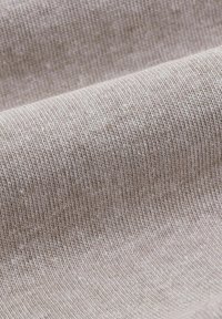 Beige ribbet strikstof med en blød tekstur og let glans, der viser fine lodrette linjer og subtile farvevariationer.