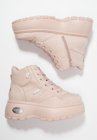 Ljust rosa ankelstövlar i mockaliknande material, med ett texturerat mönster, dragkedja på sidan och en tjock, klumpig sula med en logotypdetalj.