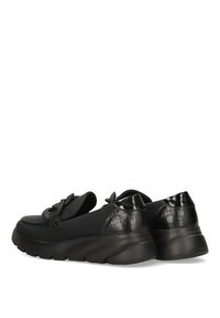 Zapatos negros con un frente de tela suave, parte trasera de textura de cocodrilo sintético y una suela gruesa; presenta un lazo decorativo en la parte superior.