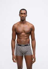 Šedé boxerky s černým pasem "BOSS" s opakujícím se vzorem loga. Vyrobeno z měkkého a pružného materiálu pro pohodlí.