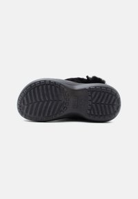 Zwarte rubberen schoenzool met een gestructureerd grip patroon en geribbelde randen. Voorzien van logo's en verhoogde details voor extra grip.