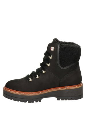 Bottines en suede noir avec doublure en fausse fourrure et design à lacets. Présente des œillets en argent, une semelle intermédiaire marron contrastante et une semelle en caoutchouc texturée.