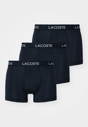 Boxers azul-marinho, pack de três. Tecido suave, cintura elástica com o logótipo "LACOSTE" em branco. Corte de comprimento médio com ajuste justo.