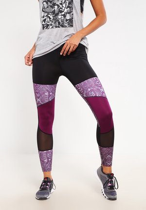 Zwarte leggings van volledige lengte met paarse en slangprint gaaspanelen. Rekbare stof met een strakke pasvorm en een gladde textuur. Gekomplementeerd met een grijze top.