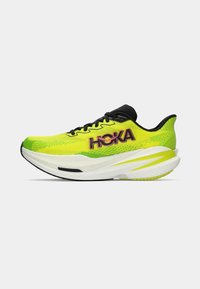 Chaussure de sport jaune fluo avec une tige en mesh respirant, des accents noirs, un logo "HOKA" bien visible et une semelle blanche rembourrée au design incurvé.