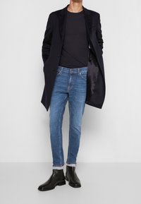 Černý kabát, námořnické tričko, světle modré džíny a černé chelsea boty. Slim fit, jednobarevné a kontrastní šití na džínách.