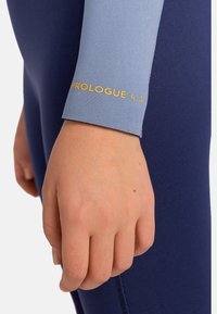 Navy wetsuit met lichtblauwe mouwen heeft "PROLOGUE 4.3" in goud op de manchette. Gladde textuur, aansluitend ontwerp en eenvoudige patroon.