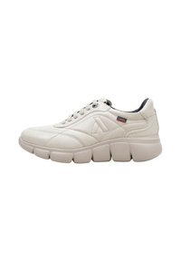 Zapatillas de color crema con parte superior de cuero texturizado, cuello acolchado y suela de goma gruesa y segmentada. Presentan un logo en el lateral.