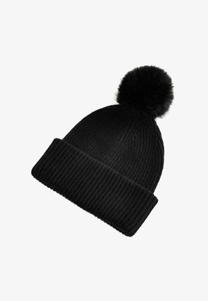 Svart stickad mössa med ribbad struktur och en fluffig svart tofs på toppen. Mössan har en uppvikt kant.
