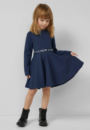 Marineblaues Langarmkleid mit ausgestelltem Rock und einem Taillenbund mit dem weißen S.Oliver-Logo. Kombiniert mit schwarzen Schnürstiefeln.