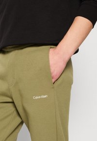 Calvin Klein MICRO LOGO - Treniņtērpa apakšdaļas - delta green