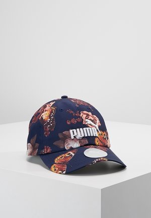 Casquette Puma bleu marine avec des motifs floraux et de papillons, logo Puma blanc brodé, visière incurvée et autocollant argenté sur la pointe.