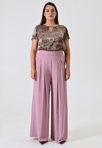 Metallic bronzen top met korte mouwen en een klein keyhole-detail, gecombineerd met high-waisted, geplooide pastelpink wijde broek.