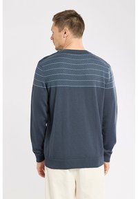 Pull en maille bleu marine avec un corps texturé et un motif rayé horizontal bleu, avec des poignets et un ourlet côtelés.