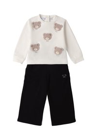 Biała bluza z pięcioma fakturowanymi aplikacjami w kształcie misiów, zestawiona z czarnymi spodniami o szerokich nogawkach z małym haftem na kieszeni.