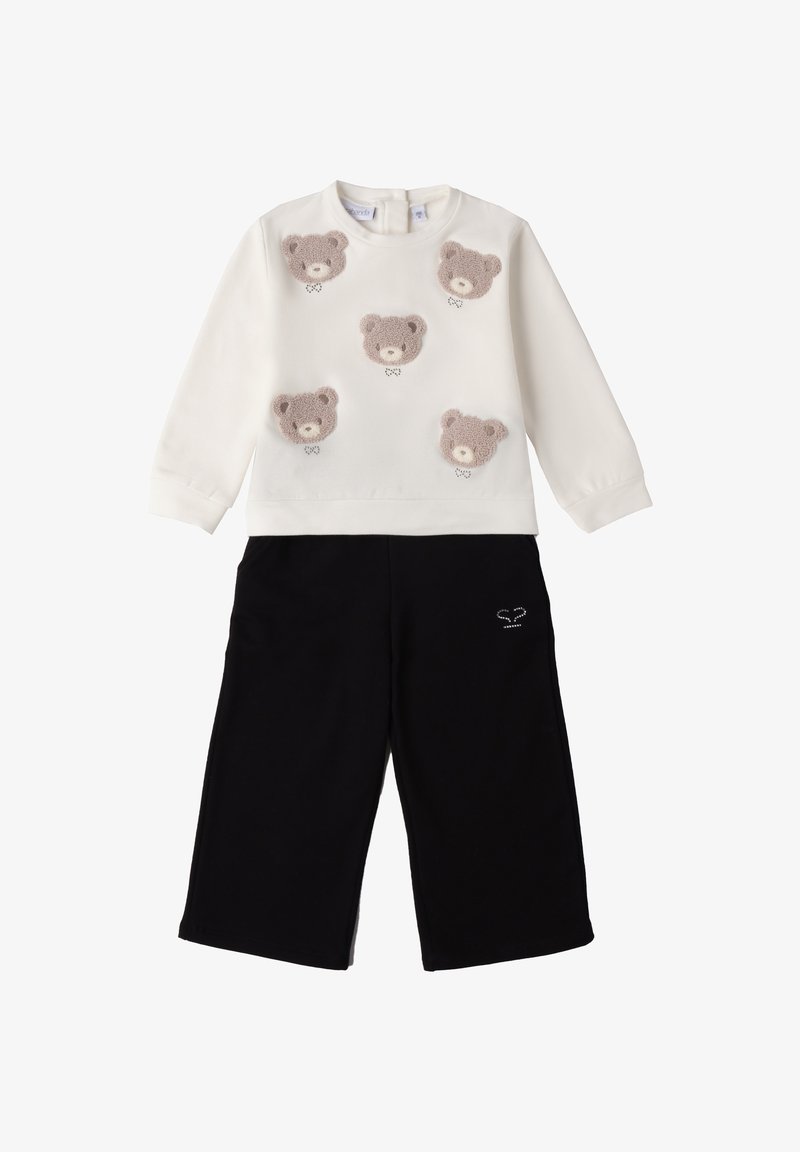 Biała bluza z pięcioma fakturowanymi aplikacjami w kształcie misiów, zestawiona z czarnymi spodniami o szerokich nogawkach z małym haftem na kieszeni.