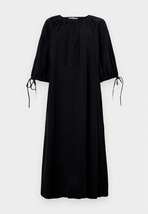 Vestido preto, largamente ajustado, com decote arredondado, mangas franzidas e detalhes de laço nos punhos. Feito de tecido leve. Cor sólida.