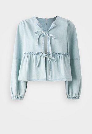 Lichtblauwe denim blouse met een V-hals, striksluiting aan de voorkant, geraffineerde taille en elastische manchet. Heeft een iets verkort ontwerp.
