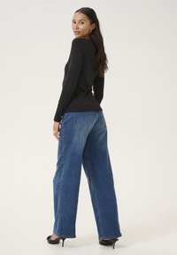 Black long-sleeve top paired with loose blue denim wide-leg jeans. The jeans feature a classic 5-pocket design and straight hems.