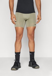 Kaki värvi sportlikud lühikesed püksid vormitud lõikega, millel on Nike logo. Kandmisel mustad sokid ja mustad spordijalanõud. Sile tekstuur.