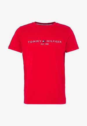 Czerwona koszulka z krótkim rękawem z białym napisem „Tommy Hilfiger EST. 1985” i małym logo flagi Tommy Hilfiger na środku klatki piersiowej.