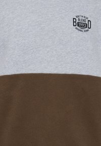 Gray and brown color-blocked sweatshirt made of cotton, featuring a small black logo on the upper left side. Smooth texture and relaxed fit.