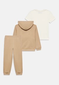 Μπεζ φούτερ με κορδόνι, ταιριαστά μπεζ παντελόνια φόρμας και λευκό μπλουζάκι. Μαλακό ύφασμα, casual σχεδιασμός, με ριμπ μανσέτες στο φούτερ και στα παντελόνια.