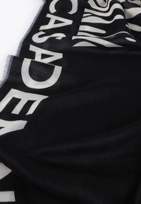 Schwarzer Schal aus weichem Material, mit auffälligem weißen Textdesign. Die Ränder sind fransig und schaffen einen strukturierten Look mit kontrastierenden Farben.