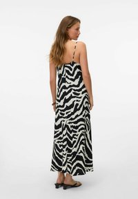 Robe maxi noir et blanc avec un imprimé zèbre, dotée de fines bretelles, d'un corsage ajusté et d'une jupe fluide qui atteint les chevilles.