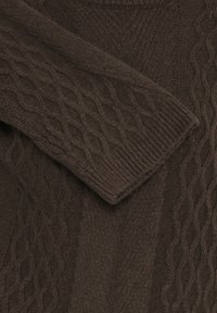 Brūns jebkurā torso daisks adījums, kas iezīmē teksturētas raksts, ribotas aproces un mīksta vilnai līdzīga auduma, ar dažādu šuvju stilus vizuālajam interesēm.