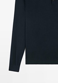 Donkerblauw poloshirt met lange mouwen, geribbelde manchetten en zoom, afgebeeld tegen een witte achtergrond.